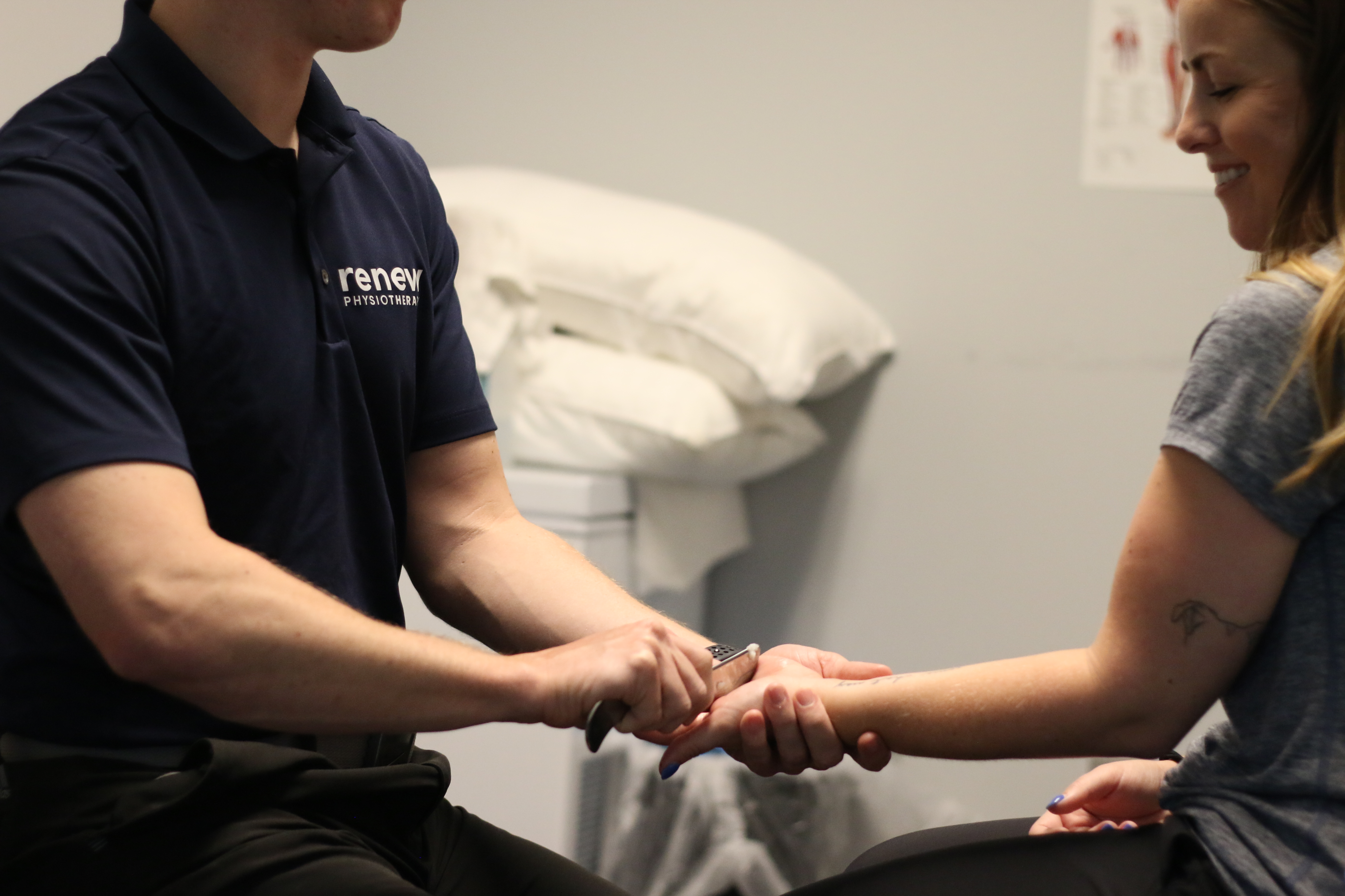 male physiotherapist performing instrument assisted soft tissue massage to a female physiotherapy client in an private office
