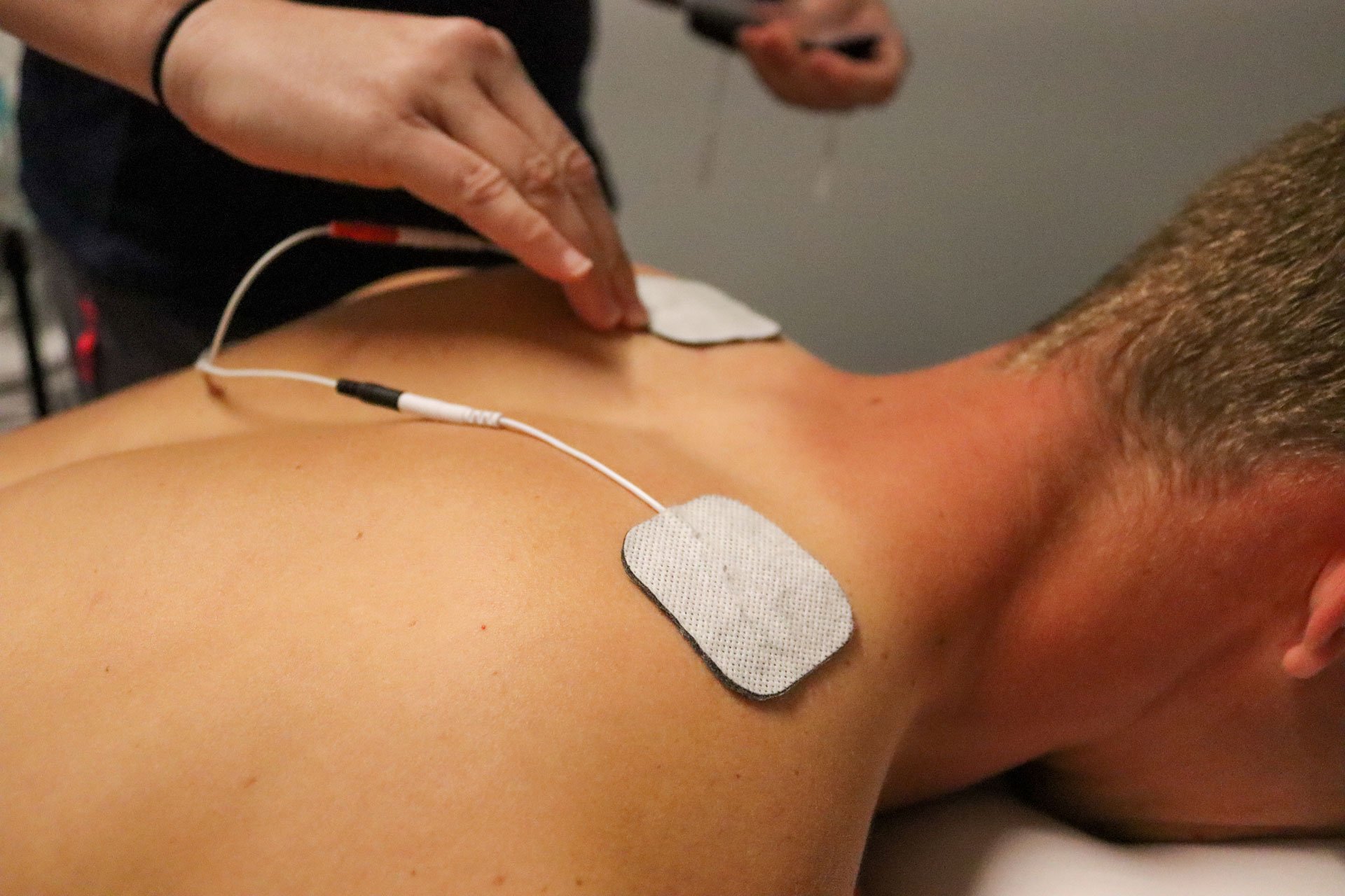 man getting electrical stimulation therapy for pain relief from a physical therapist