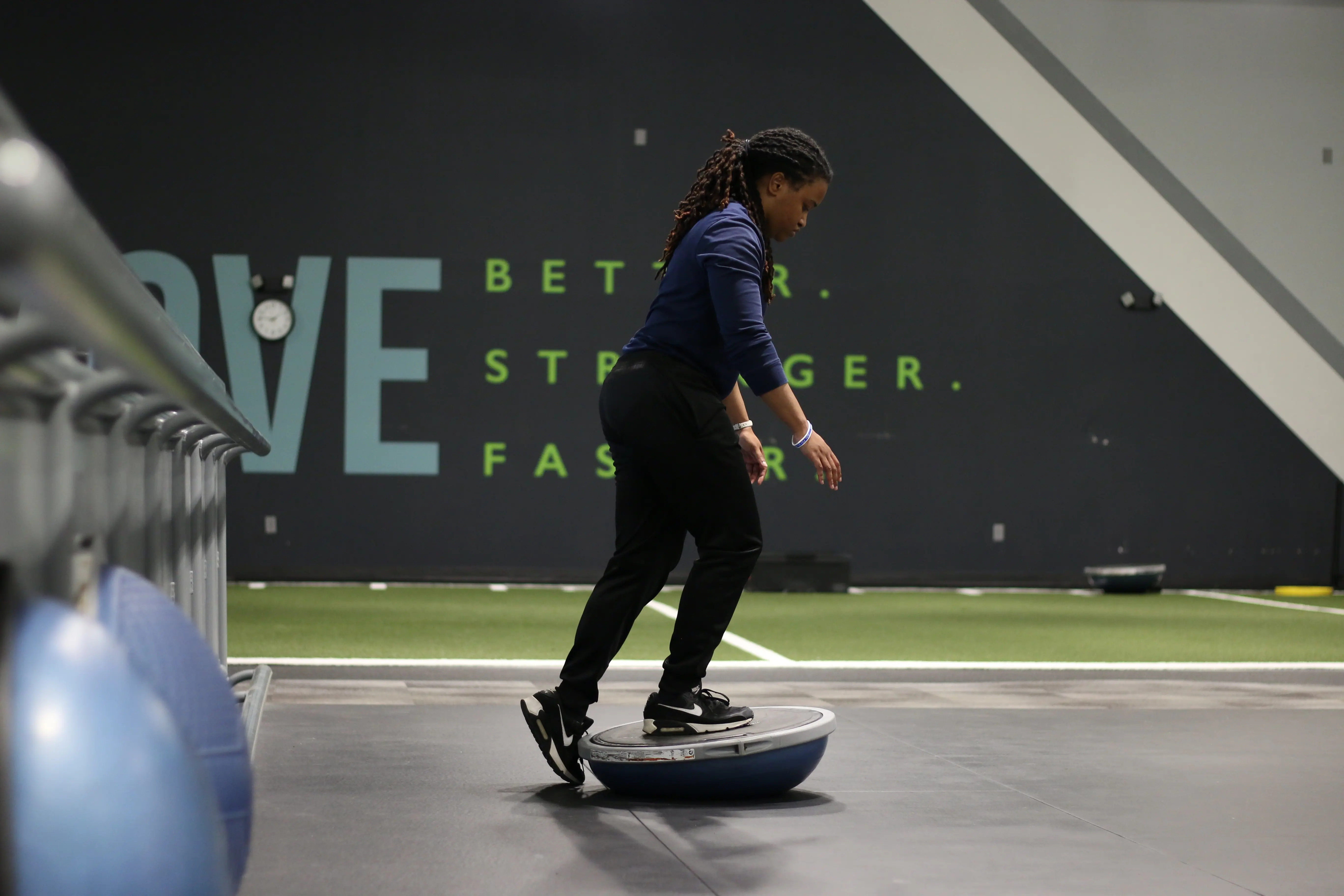Woman stepping on to a bosu ball to test her balance and stability in the gym