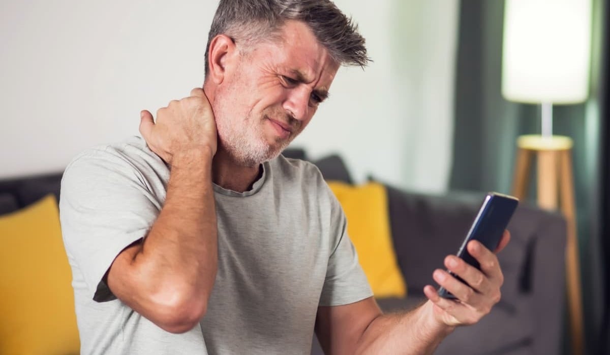 Man experiencing tech neck pain from his smartphone 