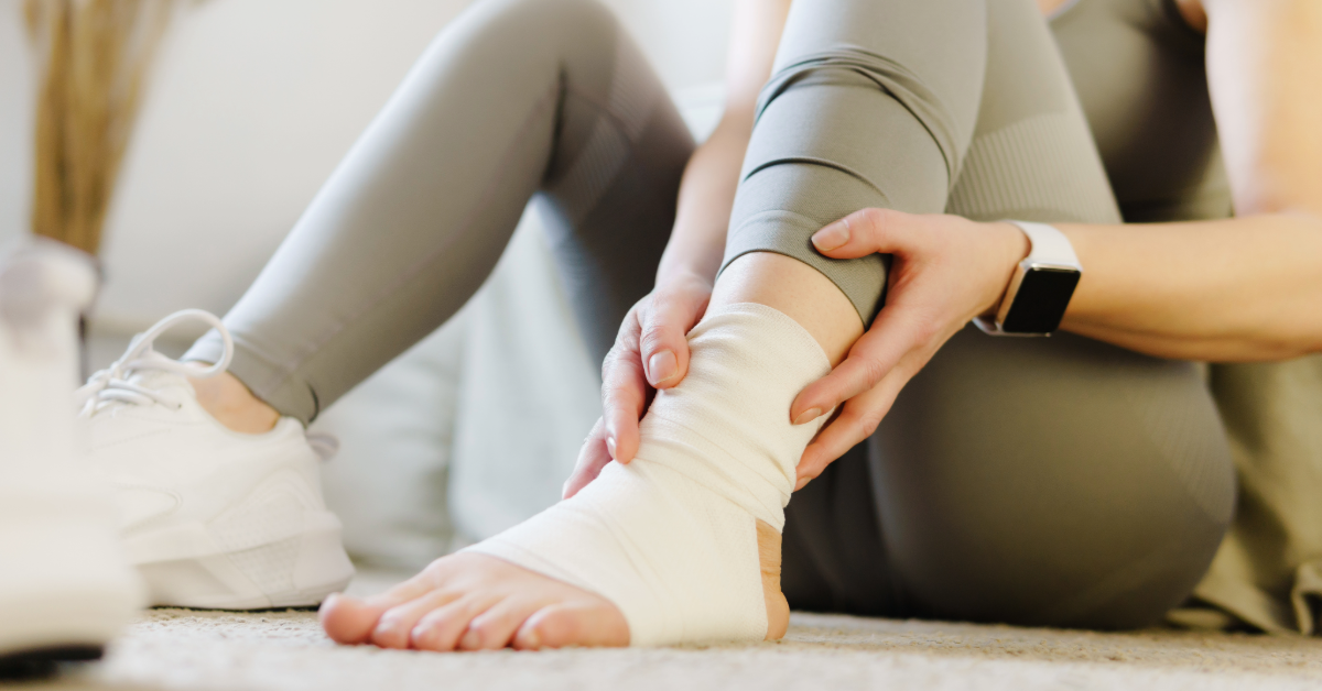 woman with wrapped ankle sitting on the floor preparing to workout