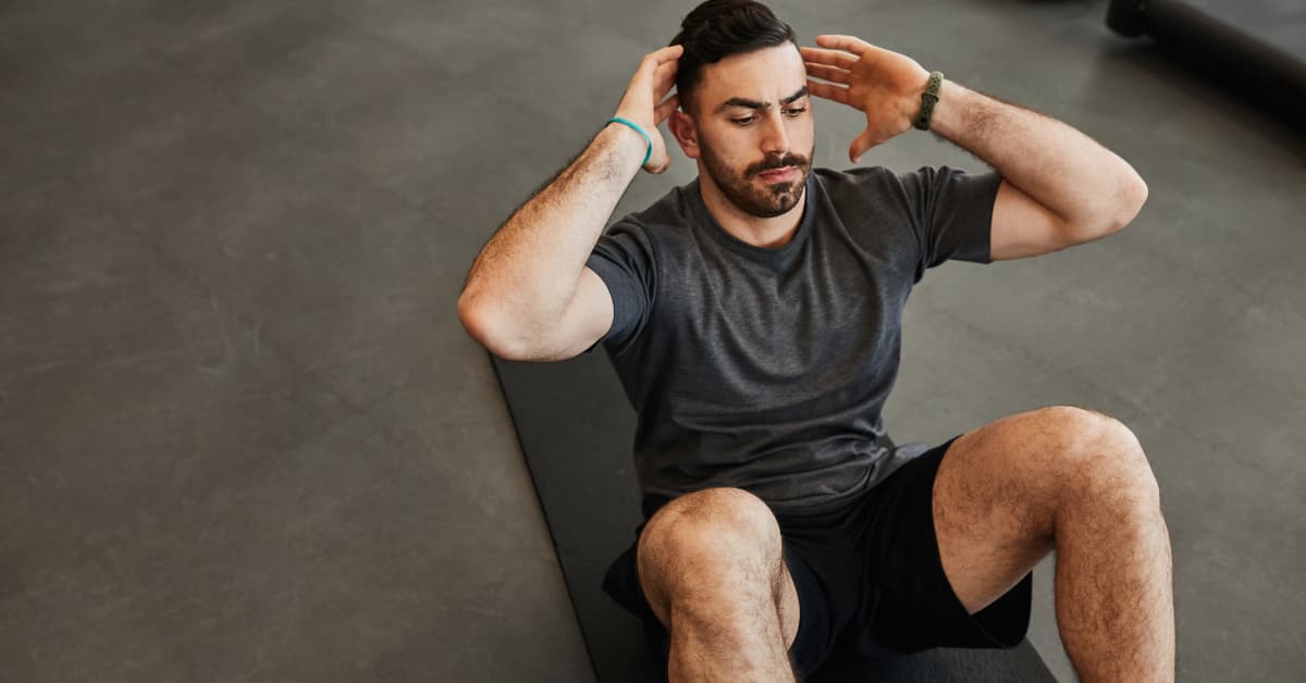 young man in a gym doing core strengthening exercises 